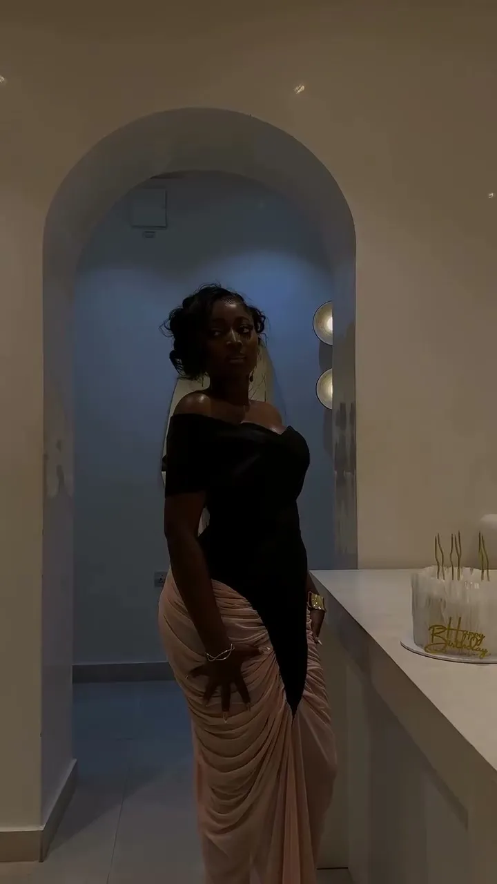A woman in a black corset with a nude draped skirt