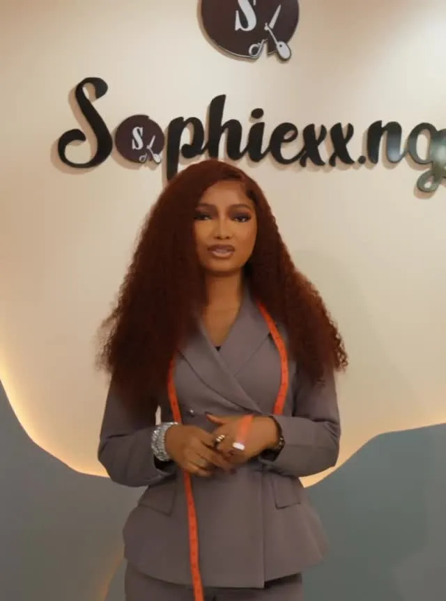 The designer in front of the Sophiexx.ng sign in the new fashion house