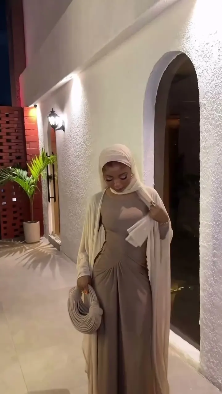 A woman in a hijab and a mocha two-piece set with a cream duster