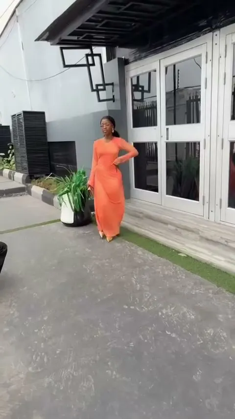The orange maxi dress walking outside