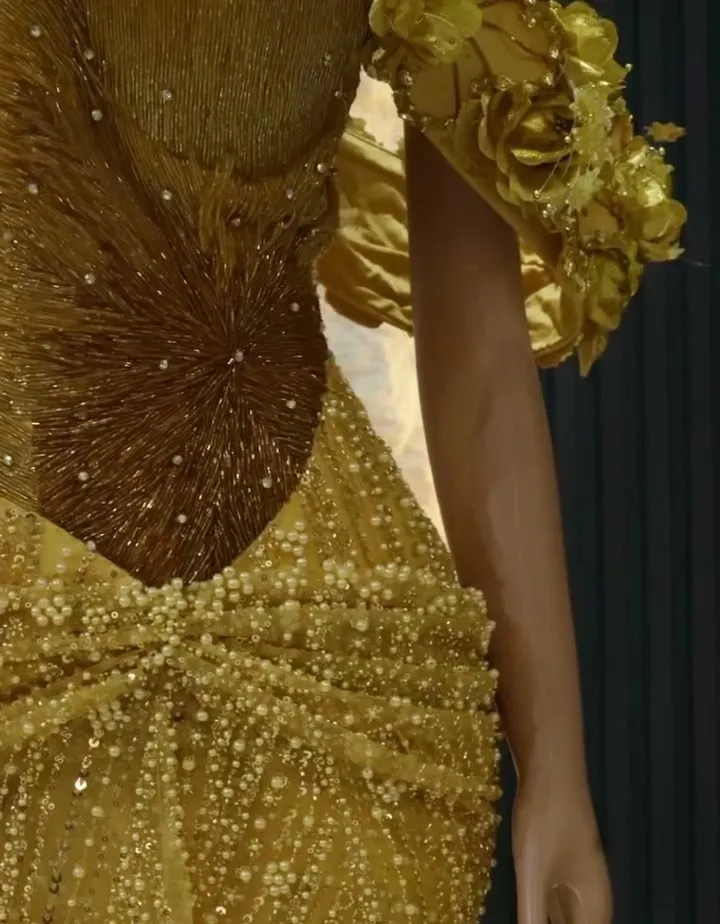 A gold beaded gown on a mannequin in the studio