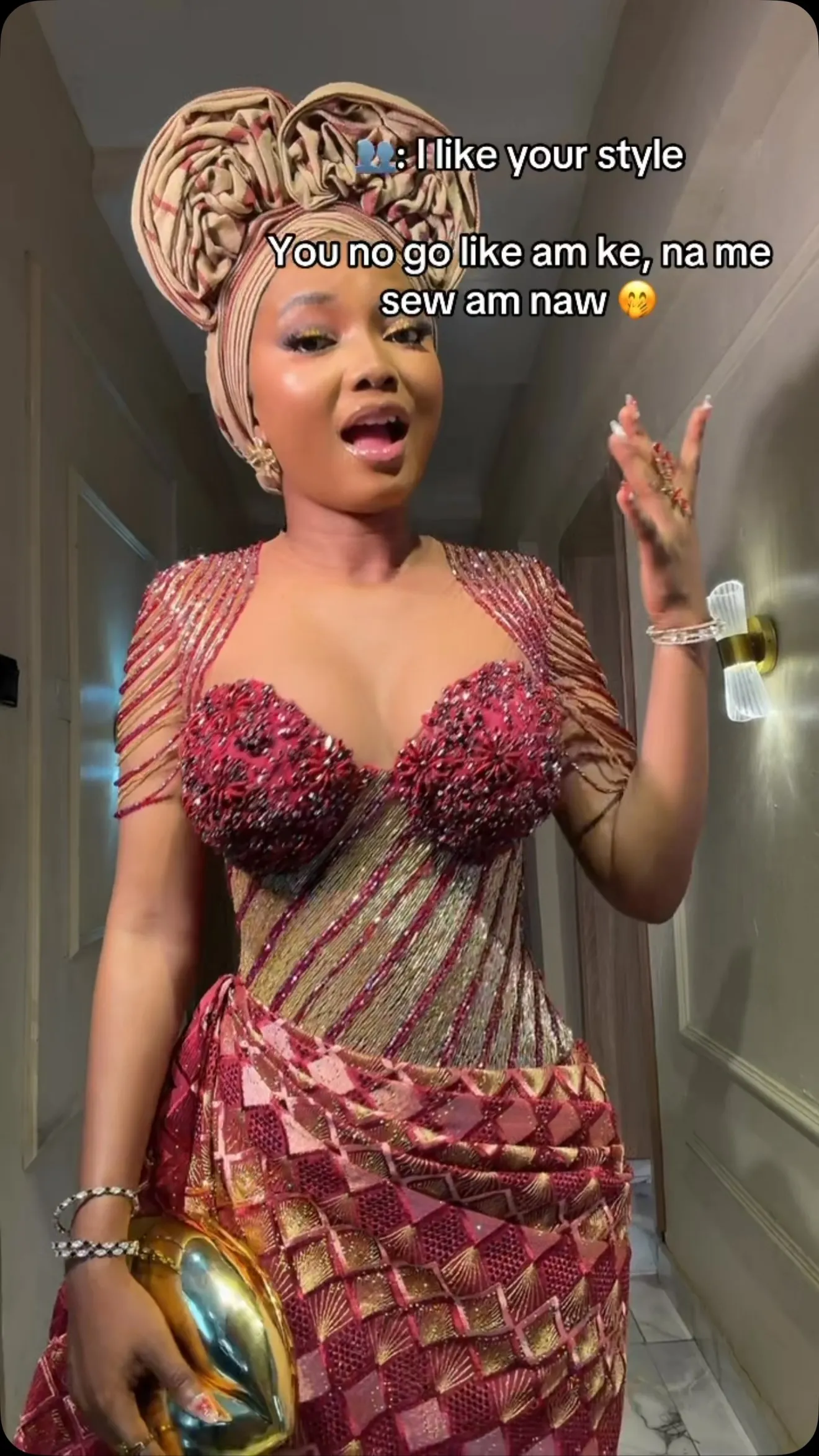 A guest in a wine and gold beaded owambe dress with a gold gele